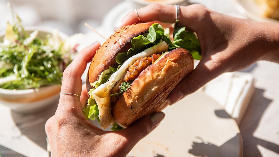 Un sandwich déjeuner tenu dans des mains.