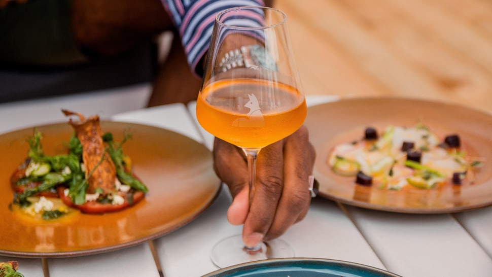 Une coupe de vin orange et deux plats servis au bar à vin Le Roux.
