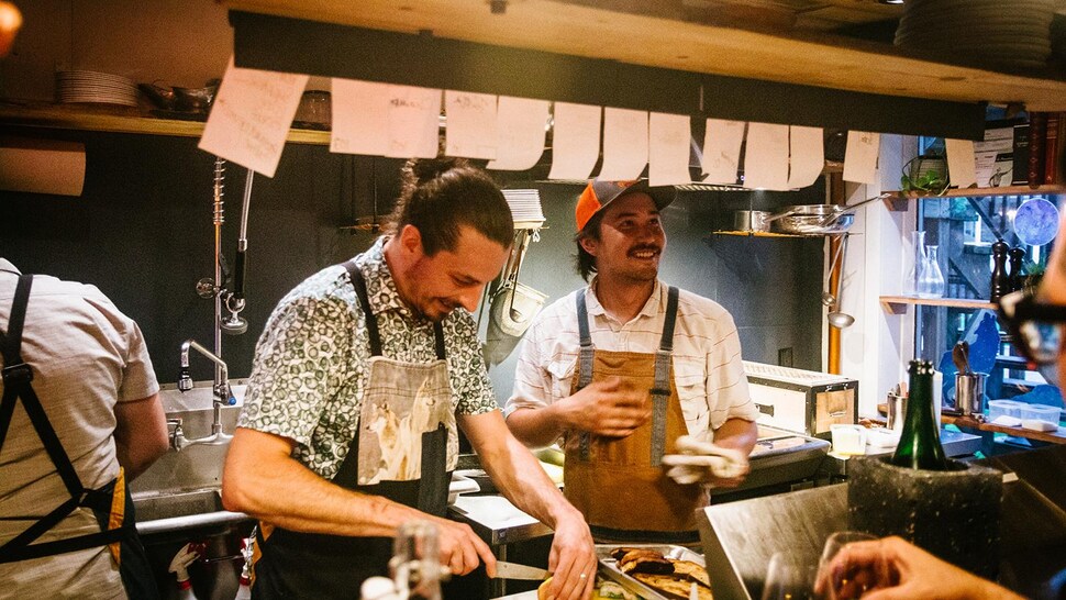 Deux hommes riant dans une cuisine.