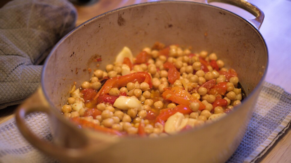 Une casserole pleine de pois chiches, de tomates et de poivrons.