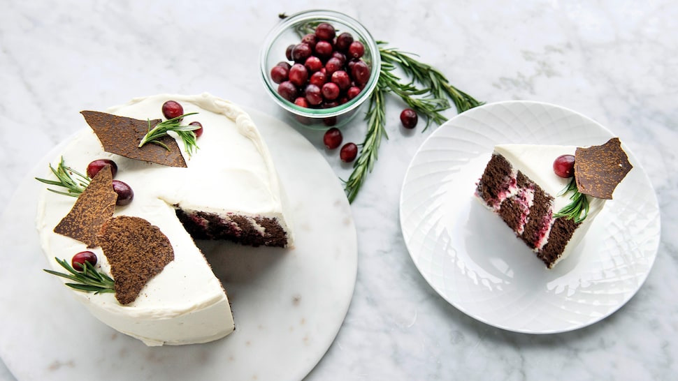 Un gâteau aux canneberges et au chocolat à côté d'un morceau dudit gâteau dans une assiette.