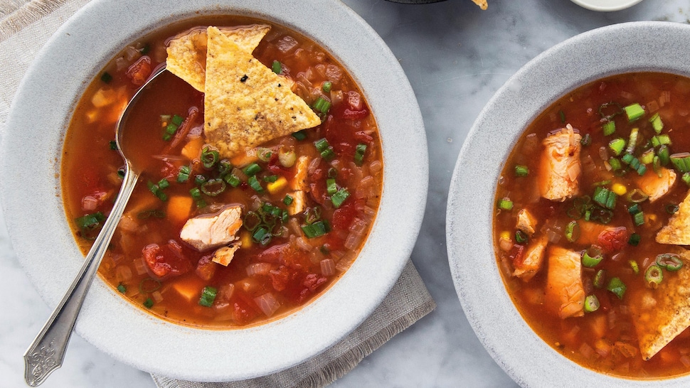 Une soupe au poulet, aux tomates et au maïs dans des bols accompagnée de tortillas au maïs.