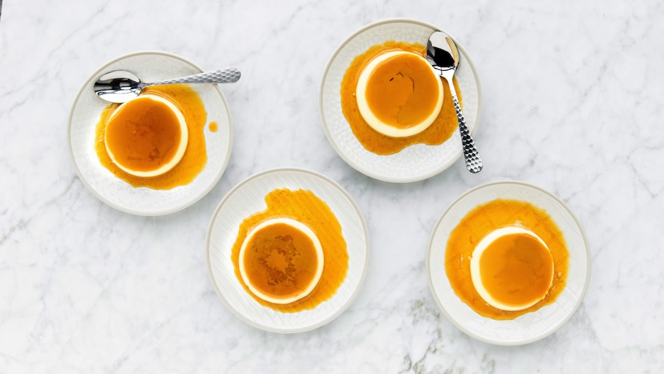 Dans quatre assiettes à dessert, il y a des crèmes caramel avec de la sauce au whisky.