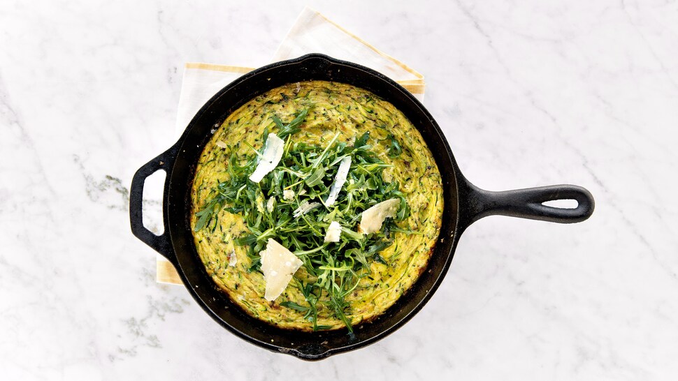Une frittata garnie de roquette et de fromage dans un petit caquelon.