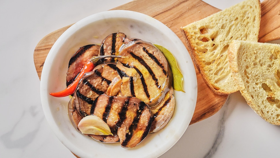 Des aubergines grillées et marinées dans un bol avec du pain.