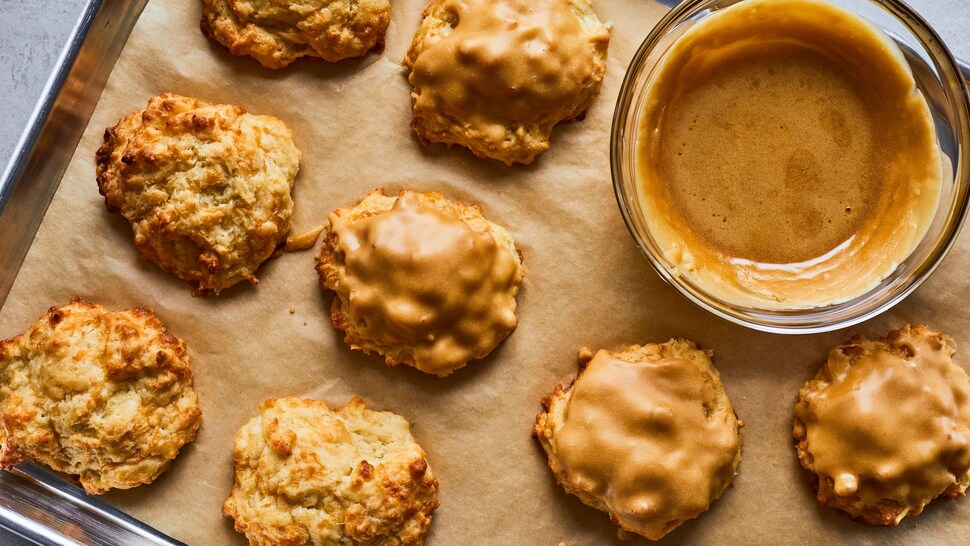 Des biscuits au cheddar et à l’érable sur une plaque de cuisson avec un bol de glaçage.