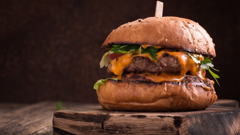 Un burger garni d'herbes fraîches et d'une sauce orangée.