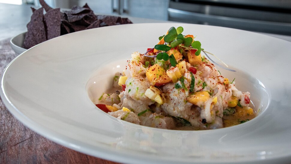 Une assiette creuse remplie de ceviche et un bol de croustilles au maïs.