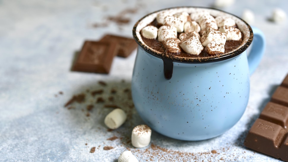 Une tasse bleue remplie de chocolat chaud avec plusieurs petites guimauves.