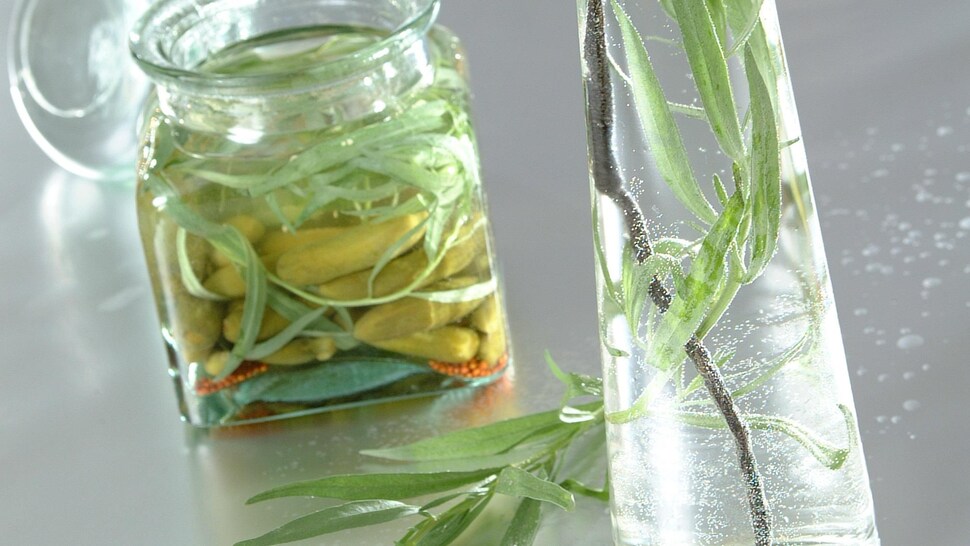 Deux bocaux en verre, un avec des cornichons confits et l'autre avec de la sauge.