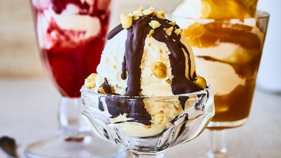 Il est possible de voir trois coupes de crème glacée, toutes avec un coulis et une garniture différente. 