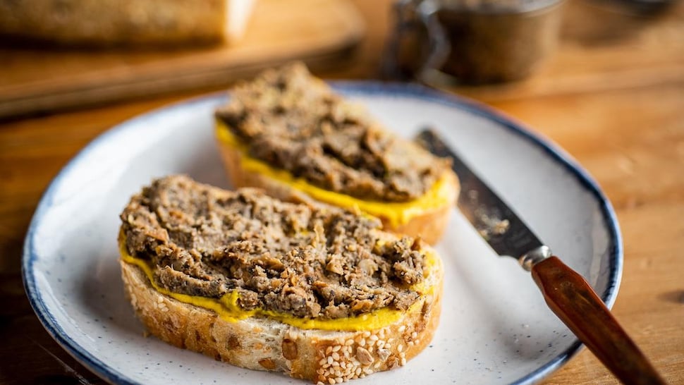 Deux tranches de pain avec de la moutarde et du creton végé dans une assiette.