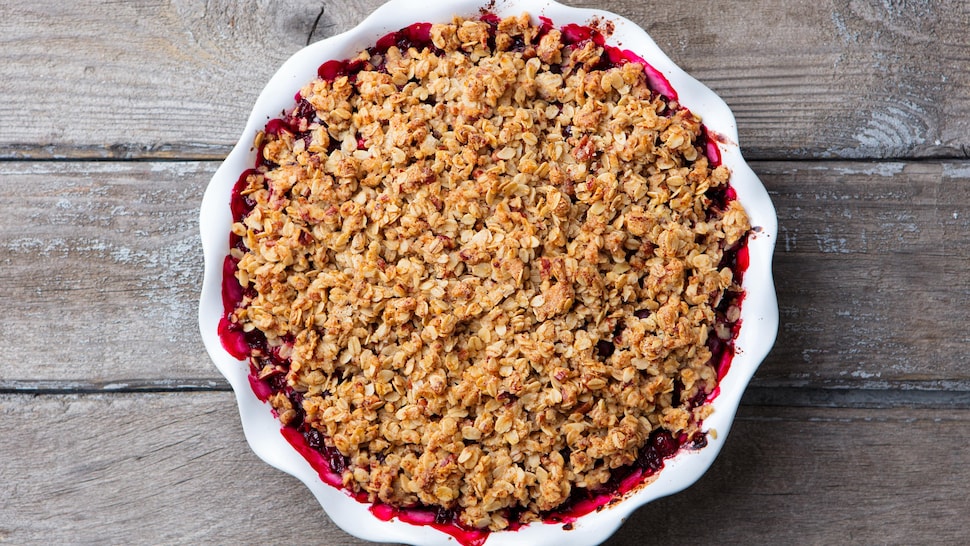 Un plat contenant de la croustade aux fraises déposé sur une table en bois.