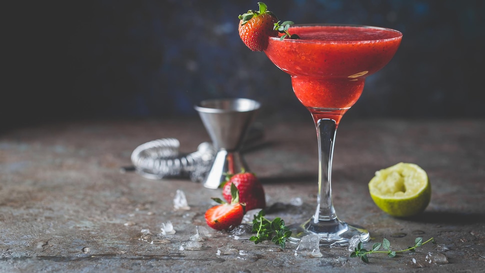 Un verre rempli de daïquiri fraises-basilic décoré d'une fraise.