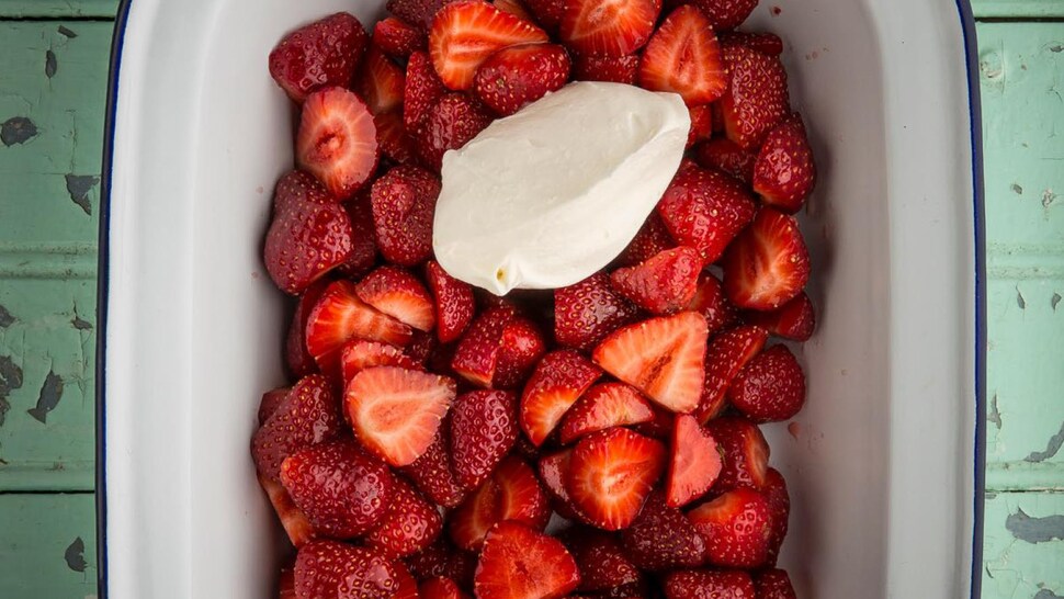 Un plat de service avec des fraises coupées en morceaux et de la crème glacée.