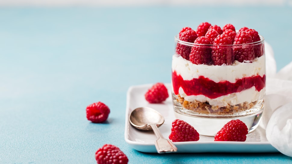 Un gâteau au fromage dans un petit pot en verre recouvert de framboises.