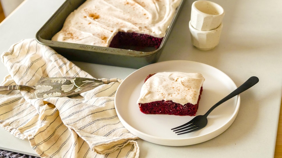 Une part de gâteau red velvet avec du glaçage, et un gâteau dans une plaque de cuisson.