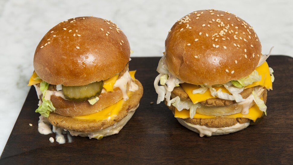 Deux hamburgers doubles végé servis sur une planche de bois.