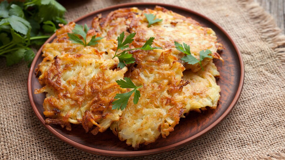 Quelques latkes dans une assiette avec quelques feuilles de persil.