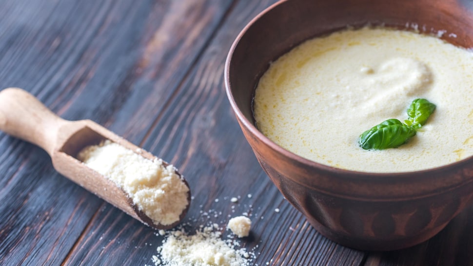 Un bol rempli de marinade au parmesan et une petite cuillère avec du parmesan.