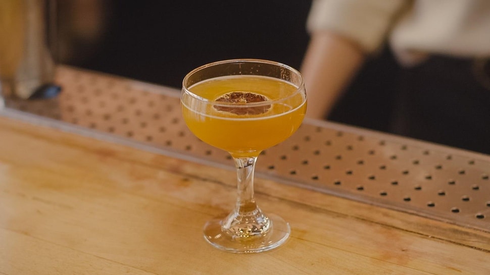 Un verre rempli d'un mocktail orangé avec une rondelle de citron déshydratée.