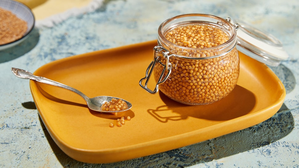 Pot rempli de graines de moutarde marinées.