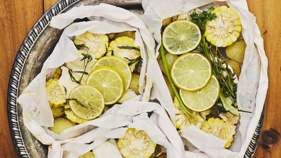 Trois papillotes de poisson au maïs sortant du barbecue.