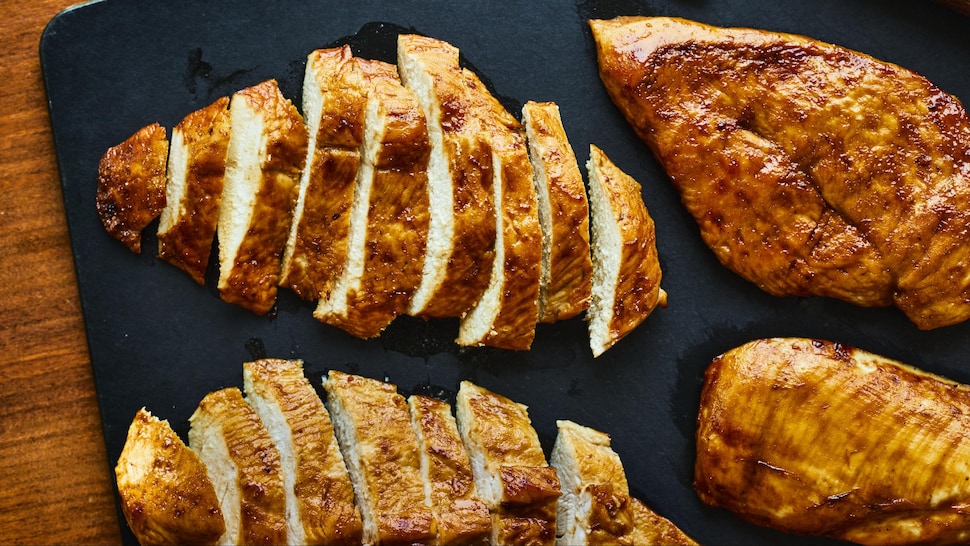 Poitrines de poulet marinées à l'érable sur une planche à découper.