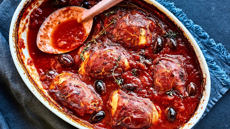 Un plat de poulet braisé au prosciutto et aux olives sortant du four.