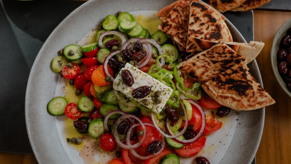 Une salade grecque composée d'olives, de tomates, de concombres et de poivrons, garnie de feta, d'olives et de câpres.