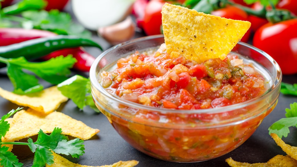 Un bol de salsa fraîche avec une croustille trempée dedans.
