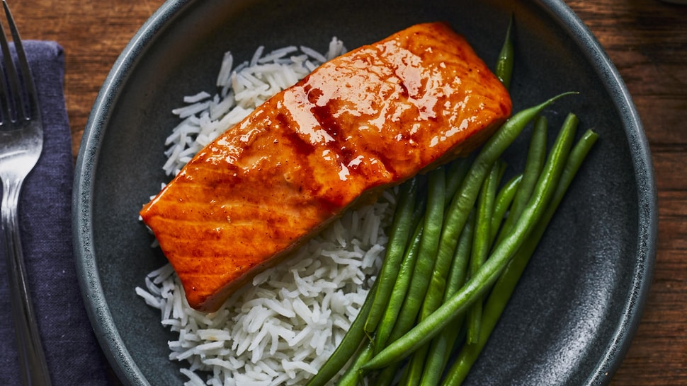 Du saumon à l’érable et à la sriracha dans une assiette, accompagné de haricots verts et de riz.