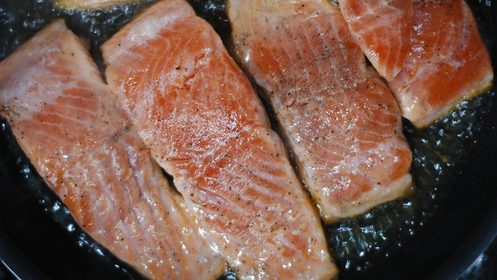 Des morceaux de saumon cuisant dans une poêle.