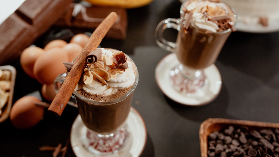 Smoothie au café dans un verre garni de crème fouetté, amandes effilées, copeaux de chocolat et d'un bâton de cannelle.
