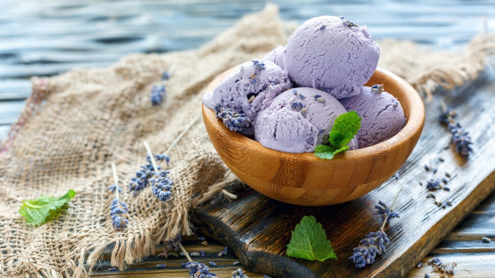 Un petit bol en bois rempli de plusieurs boules de crème glacée violette à la lavande.