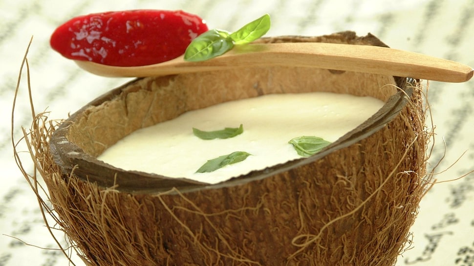 Une soupe de lait de coco au basilic et au granité de fraises servi dans une moitié de noix de coco.