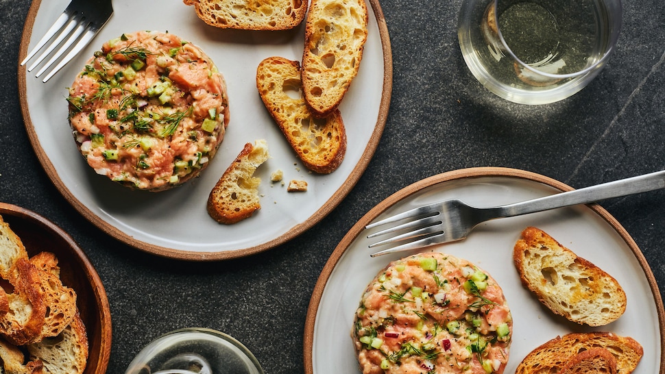 Deux assiettes contenant le tartare de saumon sur une table. 