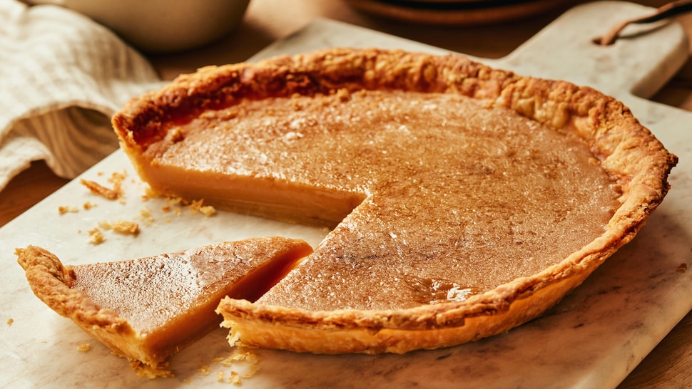 Sur une planche de bois, est déposé une tarte au sucre.