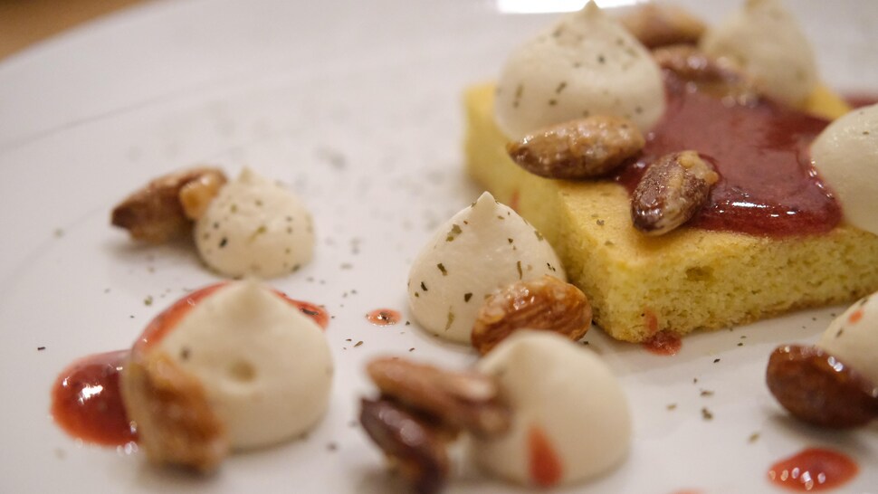 Une assiette avec un sablé breton, de la crème et des amandes. 