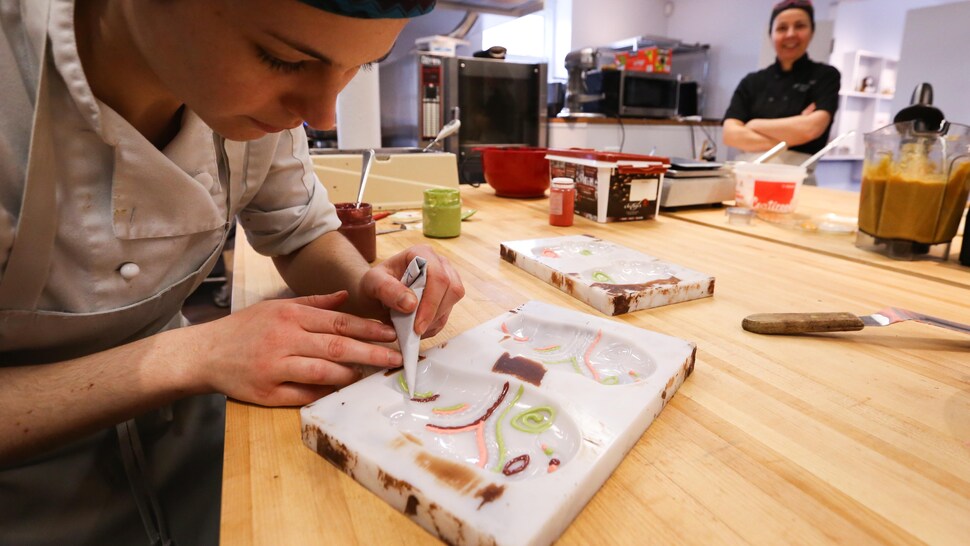 Un pâtissière travaille avec du chocolat. 