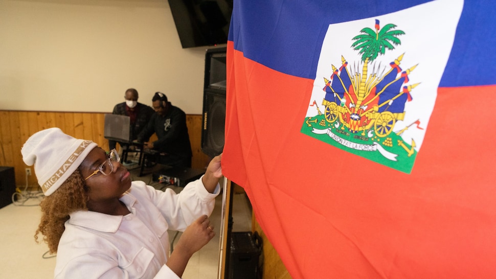 Une femme tient le drapeau d'Haïti. 
