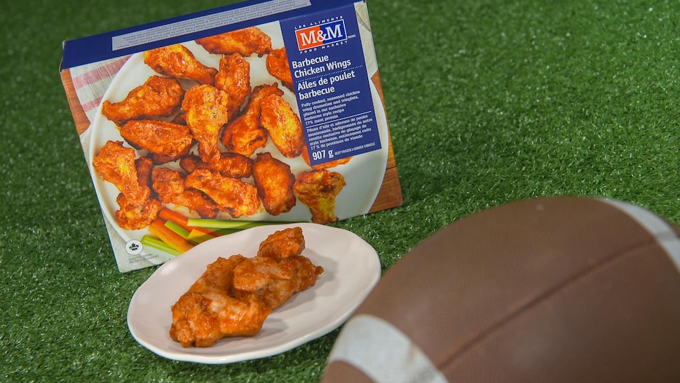 Une boîte d'ailes de poulet au barbecue de M&M, des ailes de poulet et un ballon de football.