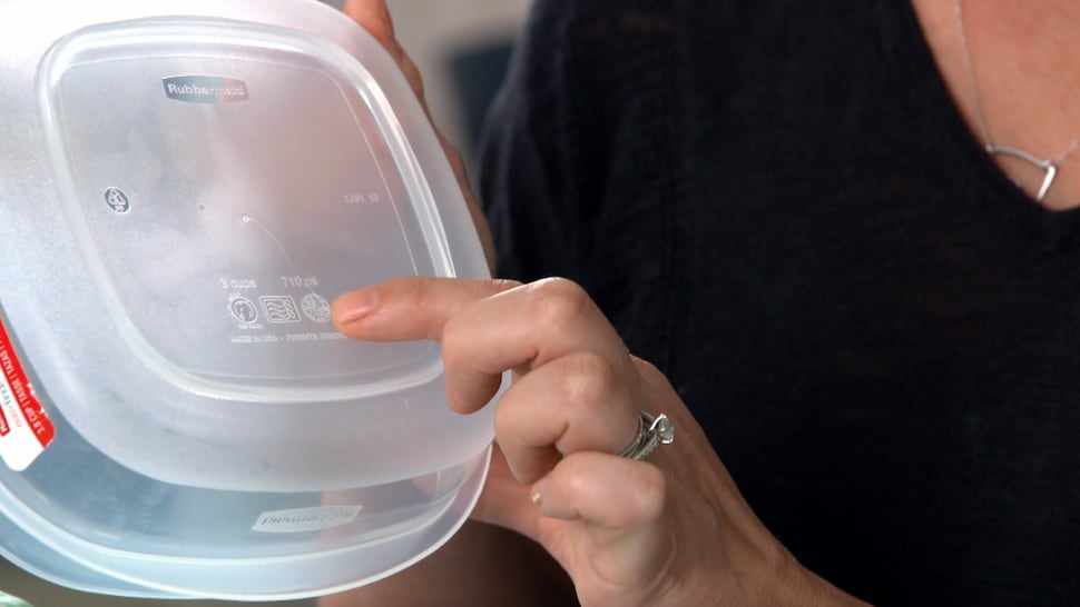 Une femme pointe un logo sur un contenant de plastique.