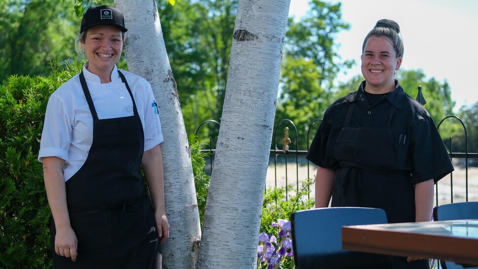 Deux femmes en habit de cuisinière regarde la caméra. 