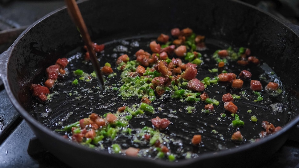 De la fleur d'ail et des lardons de bacon dans un poêlon en fonte. 