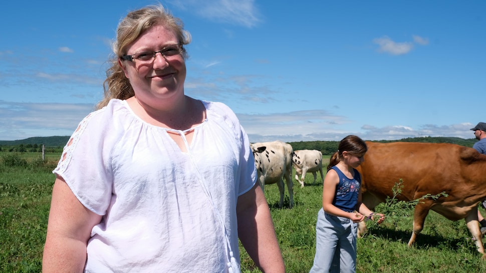 L'agricultrice devant un troupeau de vaches laitières libres dans un champ.