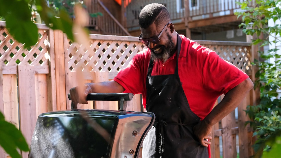 Un chef souriant en ouvrant un barbecue. 
