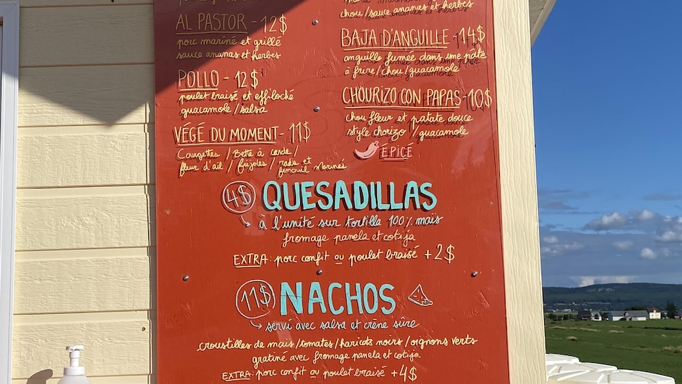 A menu with Mexican-inspired dishes written in blue on a red background. 
