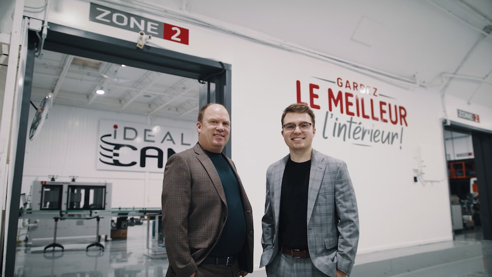 Les fondateurs de l'entreprise devant la porte d'entrée de l'usine de fabrication. 