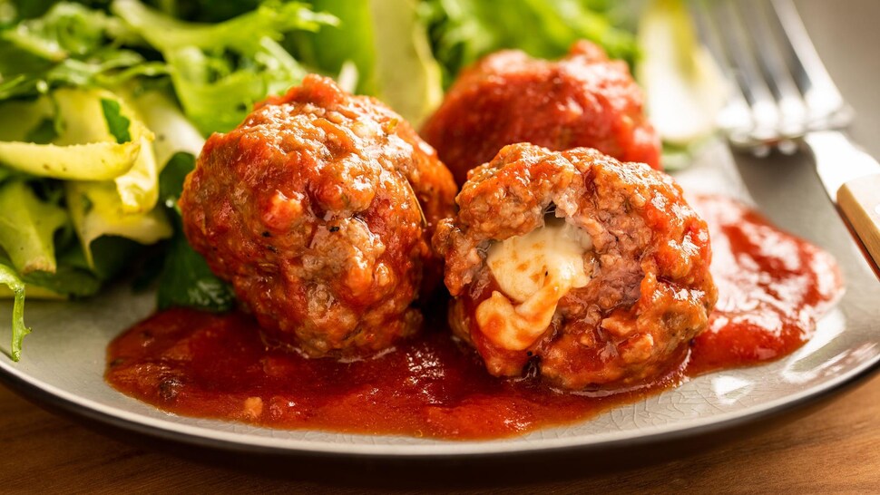 Dans une assiette, trois boulettes sont sur un lit de sauce.